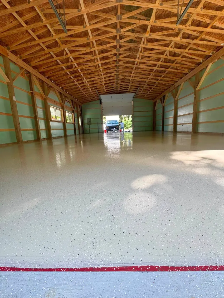 Light gray flake-coated floor beneath exposed timber roof trusses.