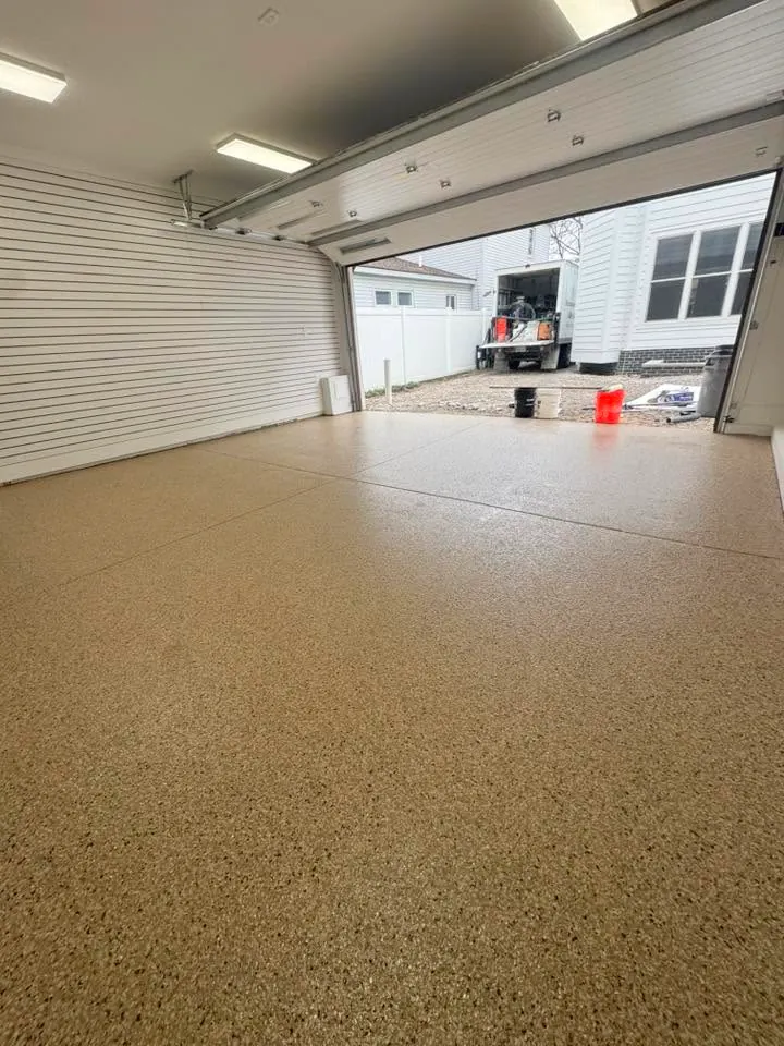 Tan flake-coated garage floor with white slat walls and an open garage door.