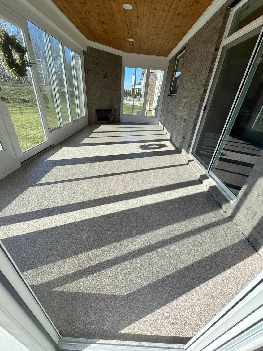 Light gray coated sunroom floor with brick walls and long window shadows.