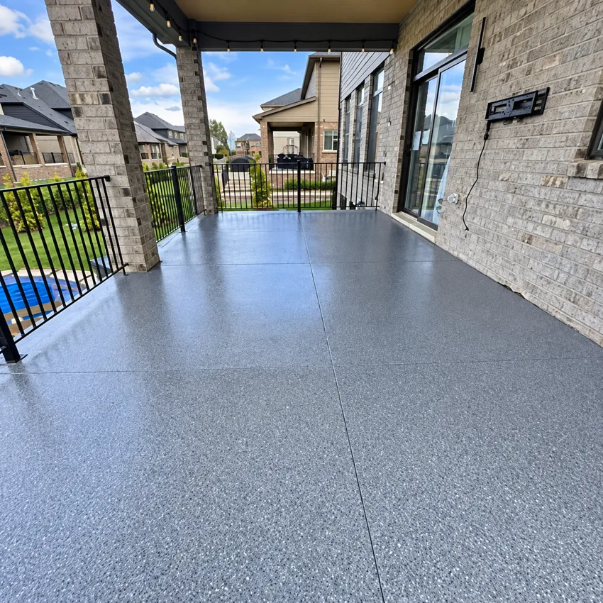 Gray coated patio floor beside brick walls and black railings.