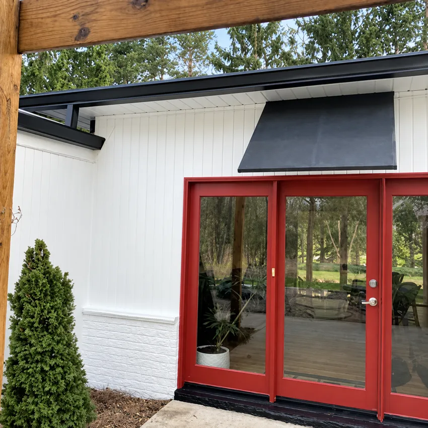 Red glass doors contrasting with white siding and a black awning.