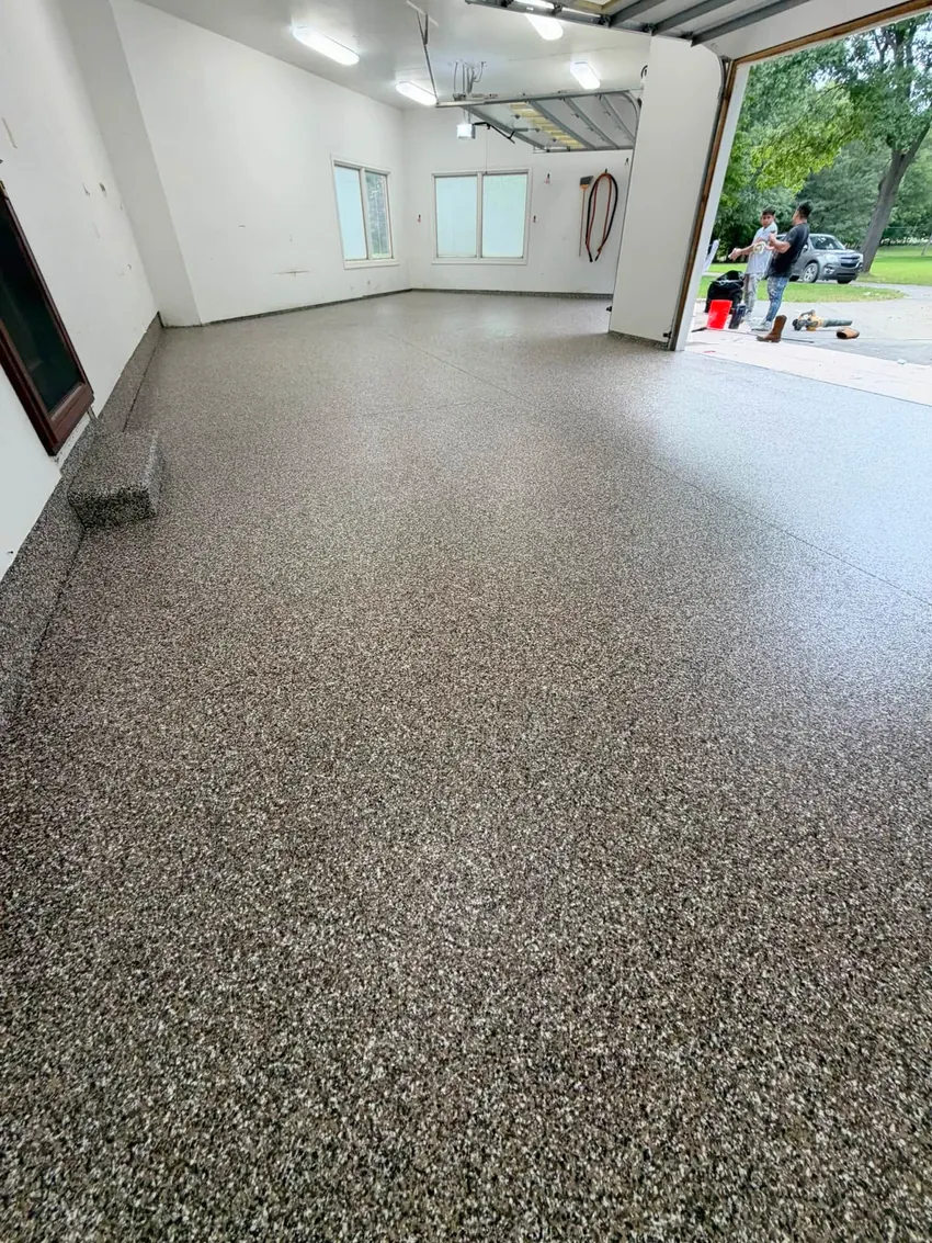 Gray flake-coated garage floor with white walls and two open garage doors.