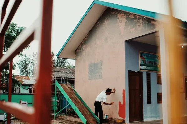 Painter coating an exterior building wall. Stock photograph.